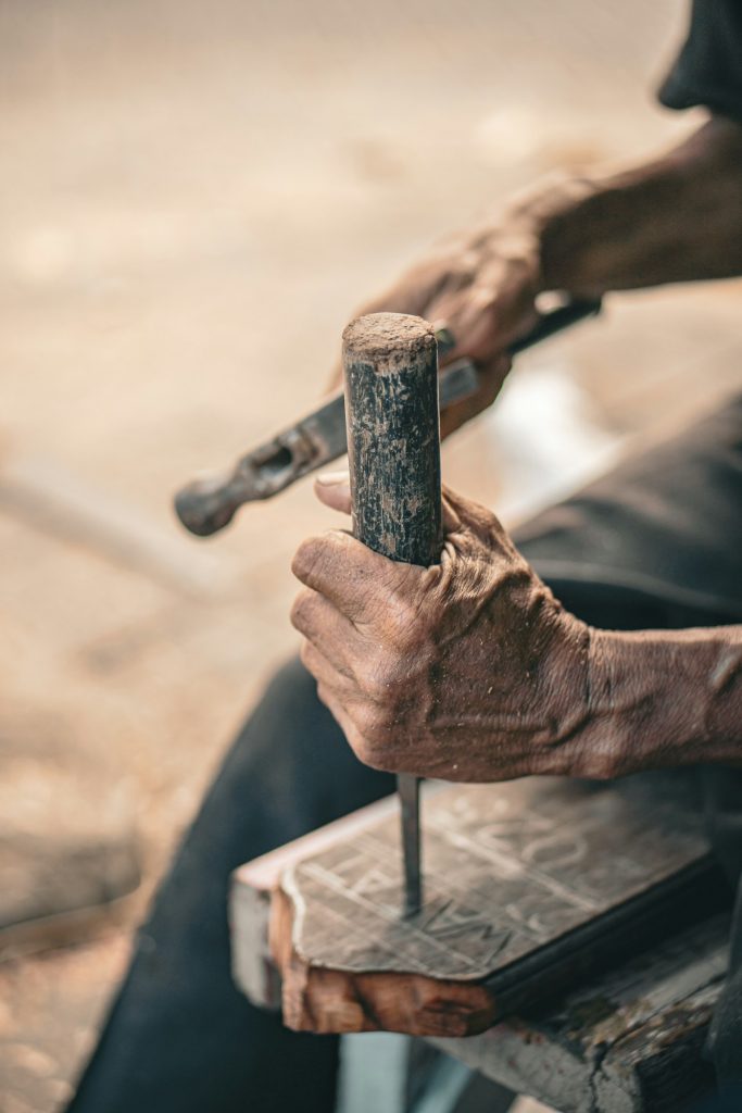 Handwerker arbeitet mit Hammer und Meißel