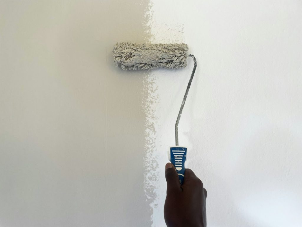 Farbrolle streicht eine Wand weiß